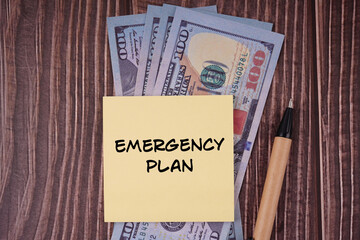 Money and life management concept. EMERGENCY PLAN written on a paper. On background of bank notes.