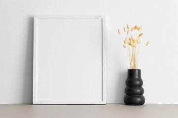 White frame mockup with a lagurus decoration on the beige table.