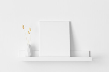 White canvas mockup with a lagurus decoration on the wall shelf.