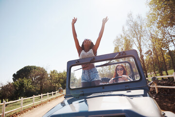 Happy women, excited and travel on road trip in countryside and bonding together for adventure in...