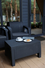 breakfast on the terrace, black tea, and cheesecake and a laptop. aesthetic breakfast on the street. white cup with tea. country recreation. rest and relaxation. working on a laptop and drinking tea.