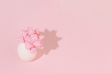 An egg with decorative bow as a gift, creative Easter composition.