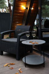 renting a chalet. table with white wine and yellowed leaves. drink wine on the terrace cabin house. autumn atmosphere. two glasses of white wine are on the table