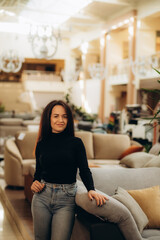 Fototapeta premium Young woman choosing sofa and pillow in furniture store. High quality photo