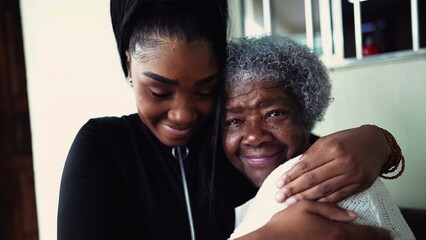 African American granddaughter hugging elderly 80s grandmother showing support and help for inter-generational family member. Family unity and love during old age