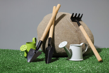 gardening tools (shovels, rakes and watering cans) near the stone