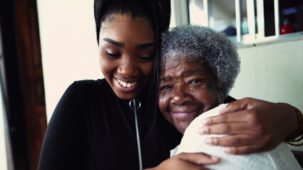 African American granddaughter hugging elderly 80s grandmother showing support and help for...