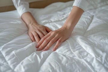 Fototapeta na wymiar Close up of hands woman putting white fitted sheet over mattress on bed.