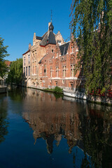BRUGGGE, BELGIUM - JULY 07, 2023: Wharf on the canal since Dijver park reflected on the water in the old town of the beautiful city of Brugge in Belgium.