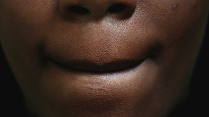Macro close-up detail of a black girl's mouth licking lips with tongue - obrazy, fototapety, plakaty