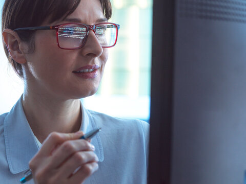 Female programmer designing code on a computer screen in the office.