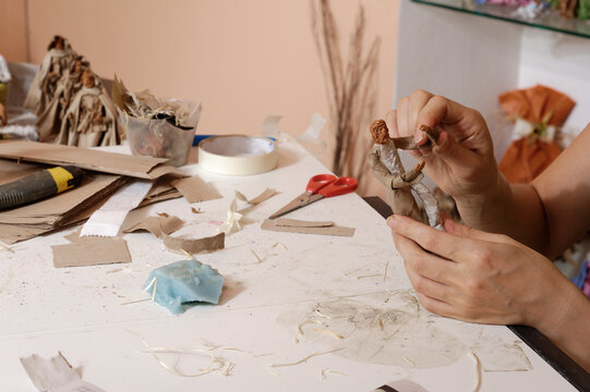 Crafting hands meticulously shaping an object amid a table full of creative materials.