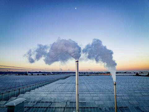 Smokestacks punctuate a serene twilight skyline