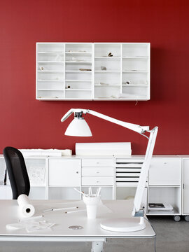 A minimalist white home office with a vibrant red wall