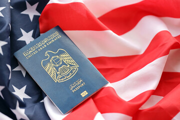 Blue United Arab Emirates passport on United States national flag background close up. Tourism and diplomacy concept