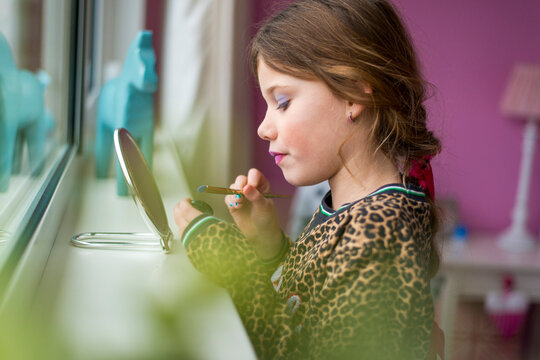 Young Girl Applying Makeup In Front Of A Mirror