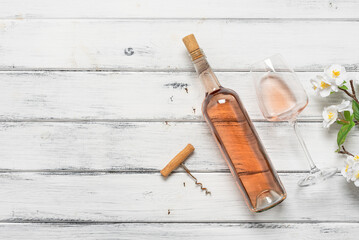 Rose wine in a bottle and glass on a white wooden background decorated with a decorative flowering cherry branch. Top view, flat lay, copy space. Pink wine. - 757231793
