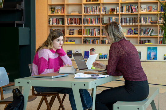 Two people in a focused study session at a library table.