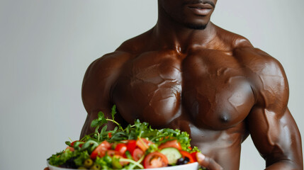 Muscular black man naked to the torso with a plate of salad. Сoncept of healthy nutrition and bodybuilding. Athletic male body and vegetables