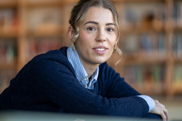Young woman smiling softly at the camera in a library setting.