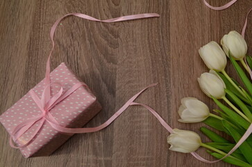 white tulips on wooden background gift in a pink box with a pink ribbon. Mothers day, Valentines Day, Birthday celebration concept. Greeting card. Copy space for text, top view
