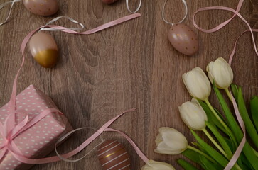 Easter concept. easter eggs in bowl ceramic easter bunnies yellow and pink tulips on isolated light beige background