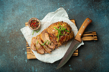 Rolled turkey roasted with spices and herbs on baking paper with knife and rustic concrete background top view. Baked cut for slices turkey fillet roll for dinner. - 757235530