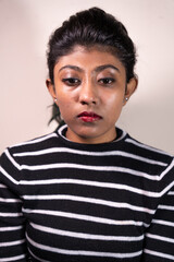 Fototapeta premium A woman with black and white stripes on her shirt is looking at the camera. She has red lipstick on and her eyes are closed