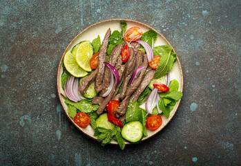 Plate with traditional Thai beef salad with vegetables and mint top view served on rustic concrete stone background, healthy exotic asian meal. - 757237300