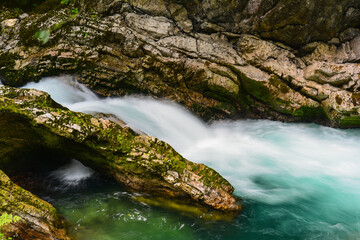 The crystal clear turquoise water of the wild Radovna river making its way through the rocky...