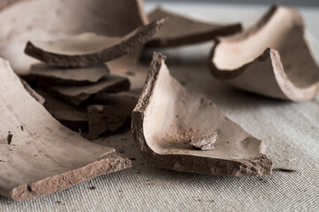 A broken clay vase in close-up. Fragments of a ceramic vase on the table. Clay broken shards in close-up. Side view.