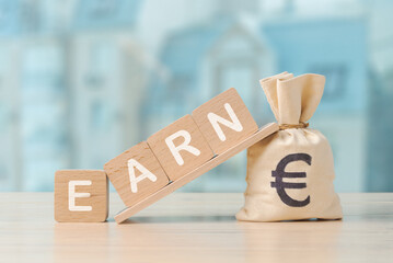 Image showcasing a money bag with a Euro symbol and wooden blocks spelling Earn, concept of earning money - 757242390