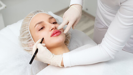 A master performs a lip augmentation procedure on a woman in a beauty salon in a beauty salon....