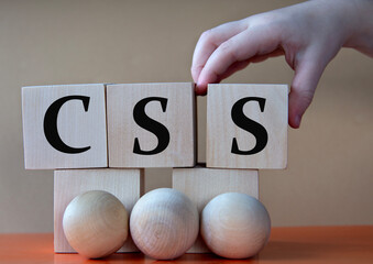 A child's hand places a large cube next to other cubes. CSS acronym concept