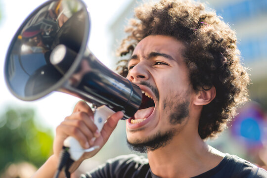 Close-up of Young man shouting in megaphone at protest