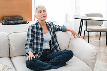 Relaxed Caucasian middle-aged woman having rest on the couch in the living room. Mature housewife...