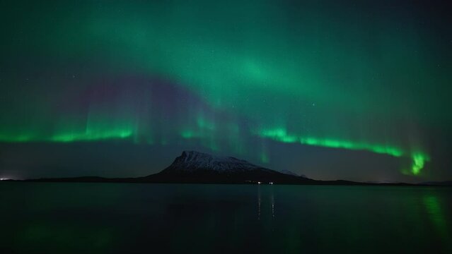 Northern lights dancing elegantly above a snow covered island in the fjords of northern Norway