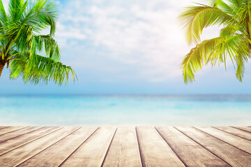 Top of woodeen table with turquoise water, coconut palm trees and blue sky background.
