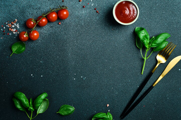 Kitchen banner. Cutlery, vegetables and spices on a dark stone table. free space for text.