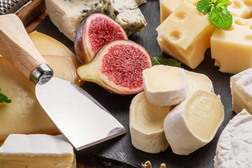 Variety of sliced cheeses with fruits, mint, nuts and cheese cutting knives. - 757257550