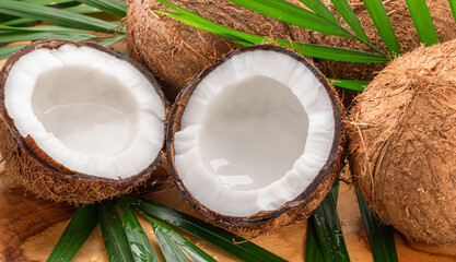 Fresh opened coconuts along with whole coconuts and coconut leaves on a wooden table. - 757257576