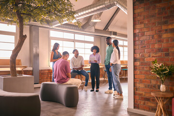 Multi-Cultural Business Team Having Informal Meeting Standing In Modern Open Plan Office Together