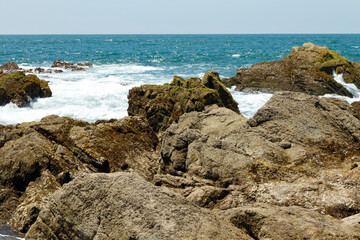 Fototapeta na wymiar Playa soleada con piedras y olas rompiendose en las rocas. Mazatlan, Sinaloa. Océano Pacífico