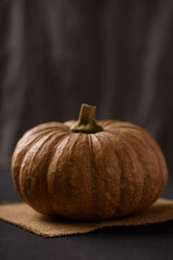Local pumpkins are placed on a brown linen cloth on a black wooden background