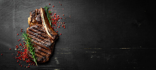 Steak on the bone. tomahawk steak On a black wooden background. Top view. Free copy space. - obrazy, fototapety, plakaty