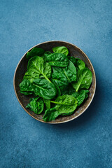 Top view of ceramic plate with fresh green spinach. Creative advertising photo. Healthy food concept. Space for text.