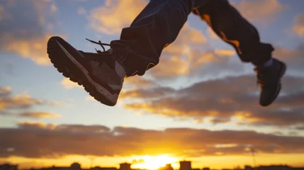 Keuken spatwand met foto Sunset leap captured from above as parkour shoes fly over an urban landscape © kitinut