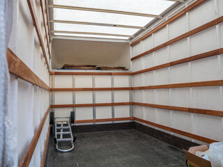 The interior of an empty removal van, with carrying trolley and packaging. Concept moving home, relocation, transport and storage. Copy space.