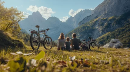 Fotobehang Two parents and their son sitting on the ground, pausing for a break at a picturesque spot along their journey by bicycles, enjoying a stunning mountainside view © Anna Lurye
