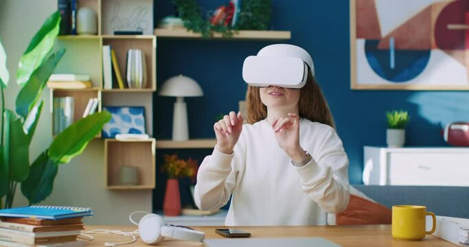 Female using glasses of virtual reality. Modern technic development. Woman gesturing while using 3D virtual glasses. Female exploring vr glasses of virtual reality. Woman sitting at office table.